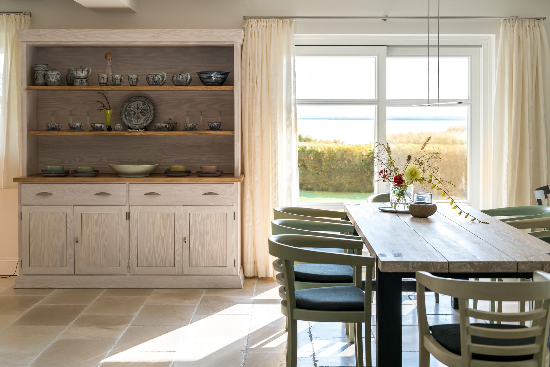 Esszimmer mit hellem Bauernschrank und Blick in den Garten